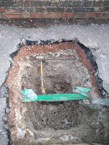 deep hole in the pavement, at the bottom which is a bundle of fibre-optic cables